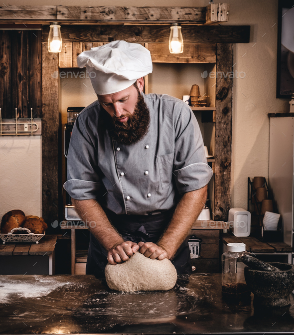 Chef teaching his assistant to bake the bread in a bakery. Stock Photo